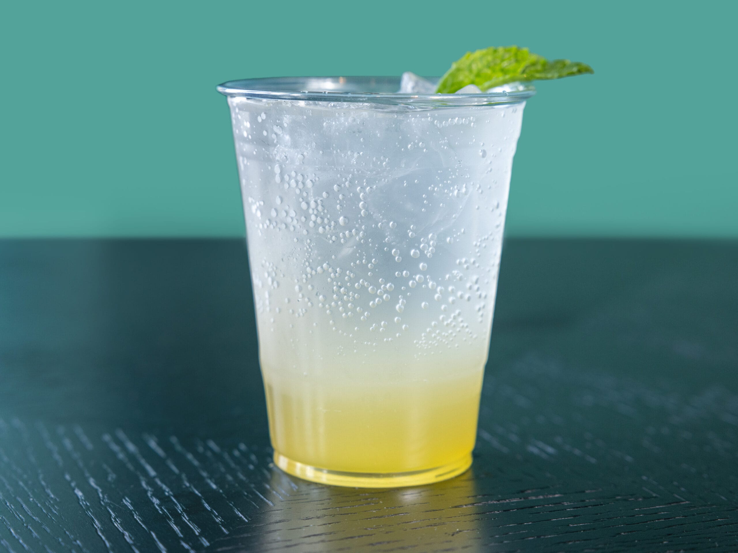 Drip Cafe Pineapple Mojito, a clear and yellow-layered sparkling drink served over ice and garnished with a mint leaf.