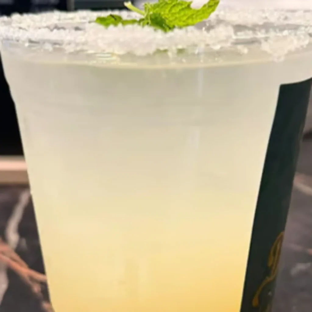 Drip Cafe Tropical Bliss Mojito, a yellow citrus-flavored drink garnished with a sugar rim and fresh mint leaves
